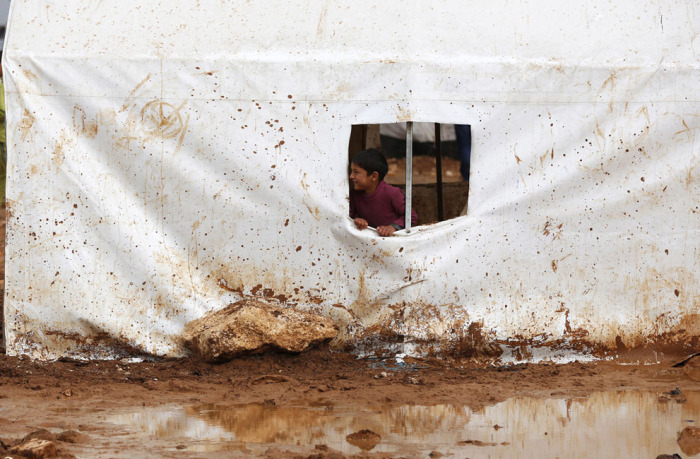 Сирийский мальчик выглядывает из палатки находящейся на территории лагеря Баб Аль-Салам беженцев в Азаза, недалеко от Турецкой границы. 14 марта 2014 года.