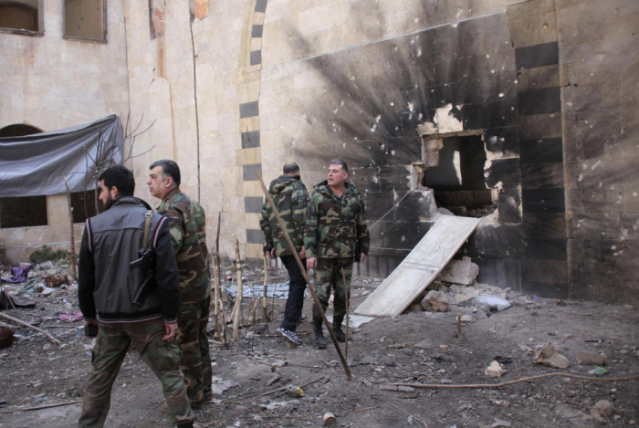 Войска, верные президенту Сирии Башару аль-Асаду возле проломленной от взрыва стены. Старый городе Алеппо, 11 февраля 2014 года.