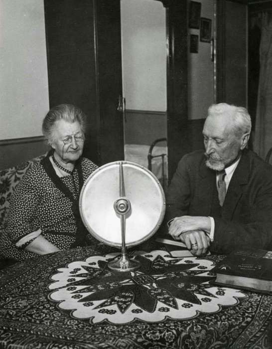 Русские аристократы, сидящие за столом и слушающие радио, проживающие в небольшом доме в пригороде Парижа. Франция, 1931 год.