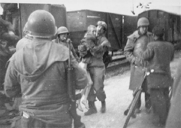 Рядовой выносит на руках истощенного человека, который самостоятельно не может передвигаться. Рядовой выносит на руках истощенного человека, который самостоятельно не может передвигаться.