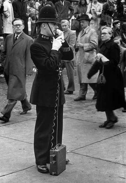 Патрульный с телефонным аппаратом патрулирует улицу и следит за порядком. Патрульный с телефонным аппаратом патрулирует улицу и следит за порядком.