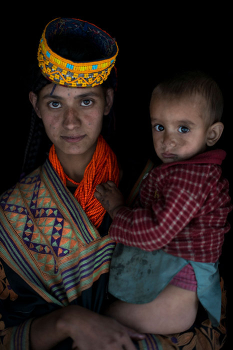 Женщина с ребенком на руках в многочисленных бусах и шапочке, украшенной бисером. Женщина с ребенком на руках в многочисленных бусах и шапочке, украшенной бисером.