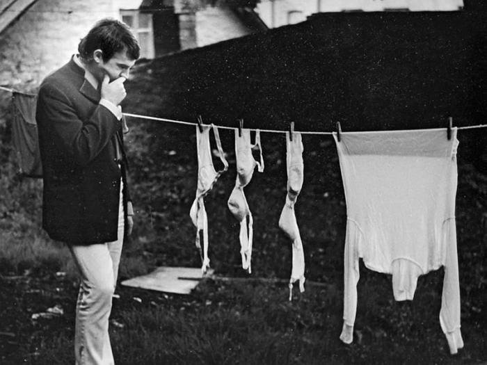 Мужчина в задумчивой позе возле сушилки с бельем.