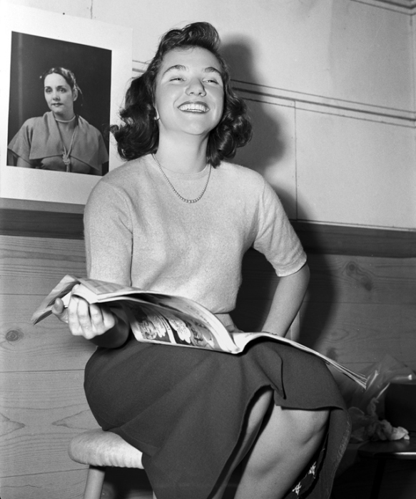 Девушка с вьющимися волосами и веселым настроением читает журнал. Девушка с вьющимися волосами и веселым настроением читает журнал.