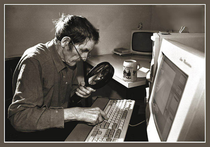 Пожилой мужчина, набирающий текст на клавиатуре. 