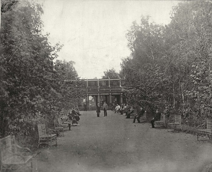 Люди гуляют на центральной аллее городского парка. 