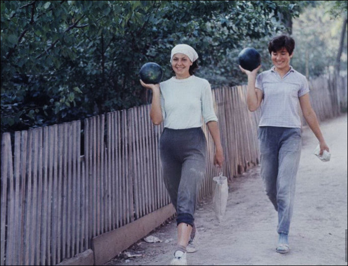 Две девушки несут арбузы после тяжелого рабочего дня. Две девушки несут арбузы после тяжелого рабочего дня.