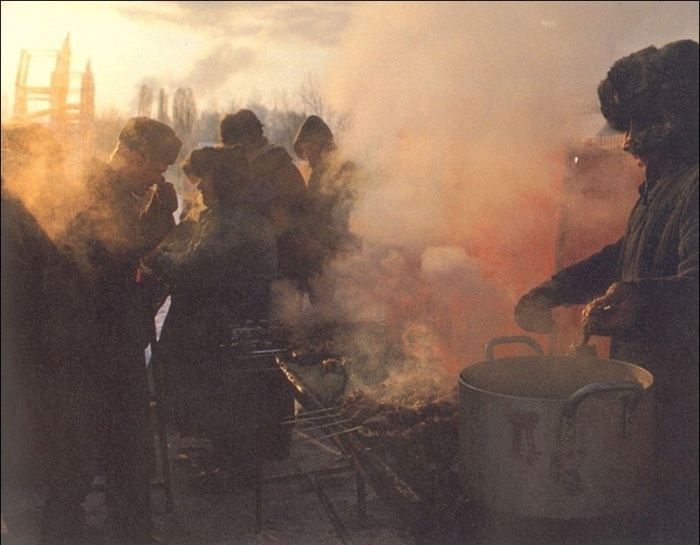 Люди собрались вокруг лотка шашлычника.