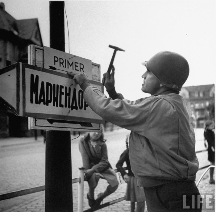 Американский капитан прибивает вывеску указатель на русском языке. Американский капитан прибивает вывеску указатель на русском языке.