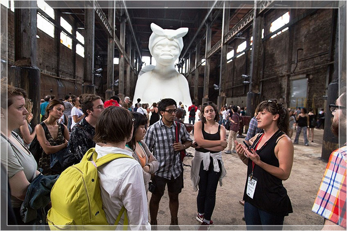 Посетители в Walker's A Subtlety. На заднем плане видна белая скульптура, изображающая женщину в образе сфинкса.