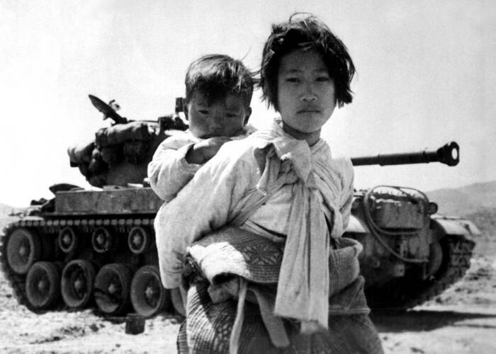 Кореянка с младшим братом на спине устало тащится мимо заглохшего танка М-26 в Хенджу, Корея, 9 июня 1951 года. Фото: bing.com.